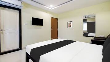 Una habitación de hotel con una cama, televisión, puerta y espejo.