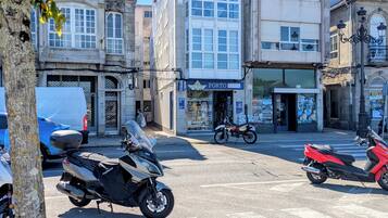 Straßenansicht mit abgestellten Motorrädern, einem Gebäude mit dem Schild 'PORTO press' und einem Baum im Vordergrund.