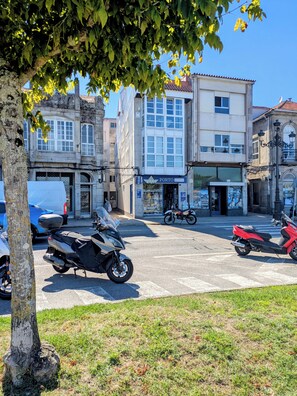 Straßenansicht mit abgestellten Motorrädern, einem Gebäude mit dem Schild 'PORTO press' und einem Baum im Vordergrund.