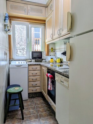 A compact kitchen with a microwave, sink, and a small stool. - Amencer Máxico ~ Downtown • Harbor Views • Parking • Ideal for Couples (Baiona)
