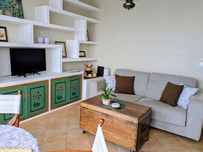 A living room with a sofa, a television, a wooden cabinet, and a tiled floor. - Amencer Máxico ~ Downtown • Harbor Views • Parking • Ideal for Couples (Baiona)