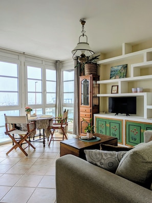 A living room with a dining area, a television, and a view of the outside. - Amencer Máxico ~ Downtown • Harbor Views • Parking • Ideal for Couples (Baiona)