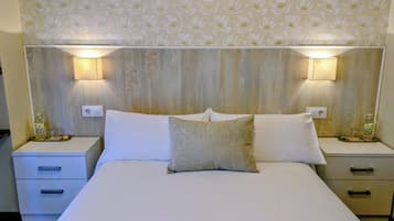 Una habitación de hotel con una cama grande, dos mesitas de noche y un cabecero estampado con motivos florales.