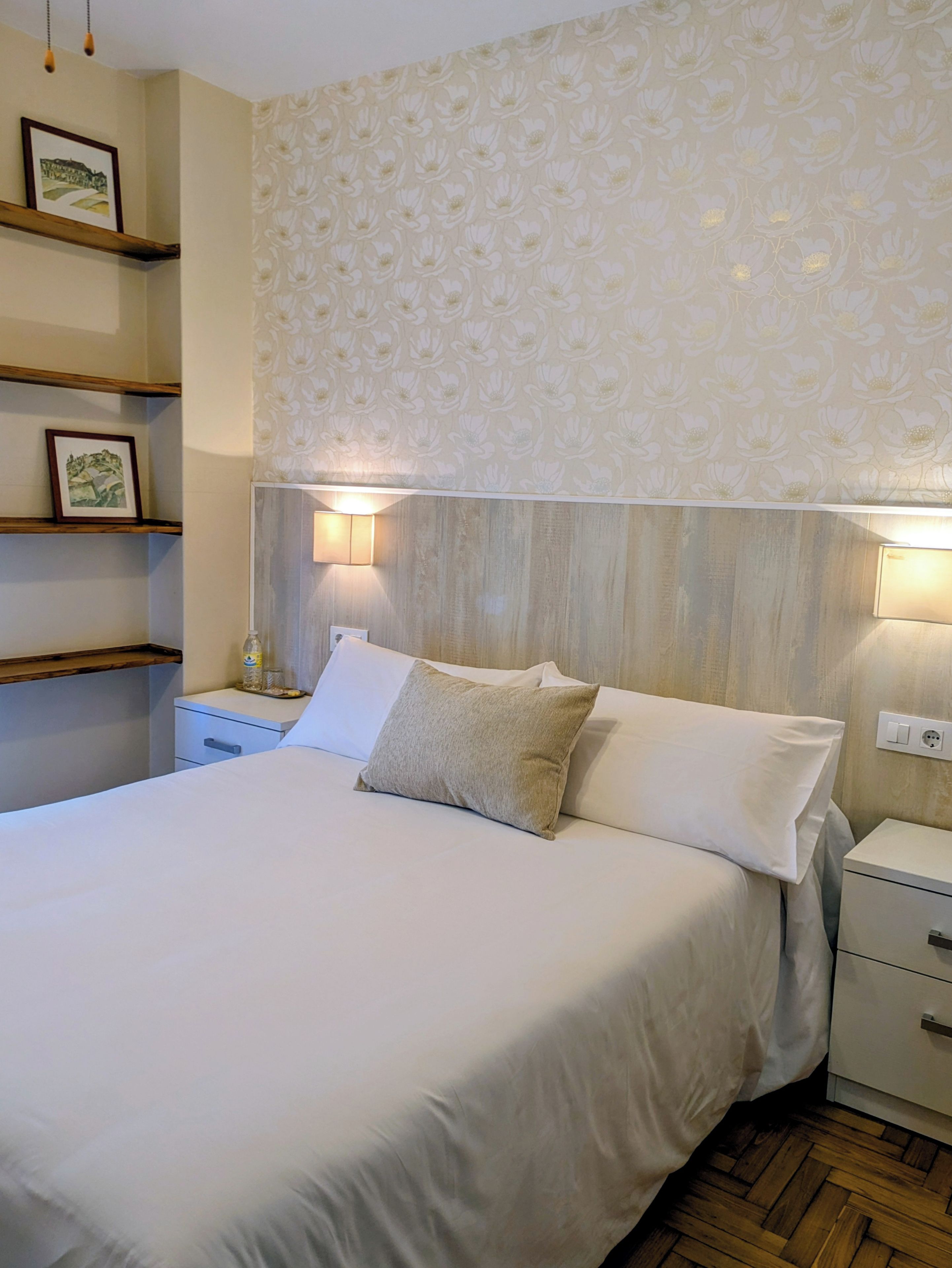 Ein ordentlich eingerichtetes Hotelzimmer mit einem Bett, Nachttischen und Wandlampen.
