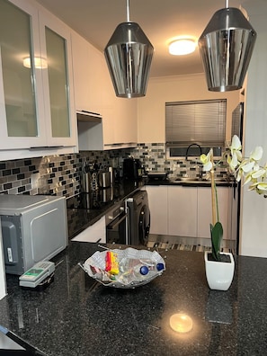 Eine moderne Küche mit Mikrowelle, Kaffeemaschine und einer Orchidee im Topf.