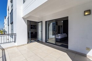 Eine moderne Wohnung mit Balkon, großen Schiebeglasfenstern, die zum Schlafzimmer führen, und einer weißen Außenwand.