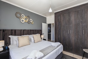 Ein Schlafzimmer mit einem großen Bett, einem Kleiderschrank und einer Wanddekoration.