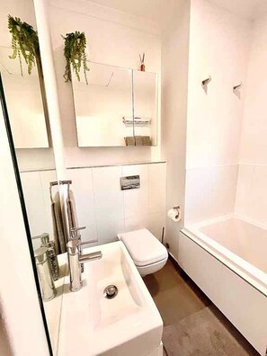 Ein Badezimmer mit einem weißen Waschbecken, einer Toilette, einer Badewanne und einem Spiegel über dem Waschbecken.