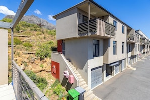 Ein Wohngebäude mit Balkon, Treppe und Garage.