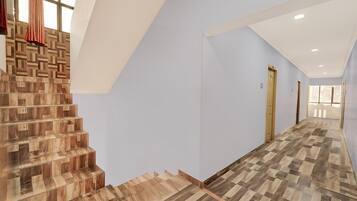 A modern interior with a wooden staircase, a light blue wall, and a hallway leading to a door.