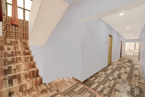 A modern interior with a wooden staircase, a light blue wall, and a hallway leading to a door.