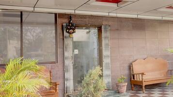 Entrada de hotel con piso a cuadros, un banco de madera y plantas en macetas.
