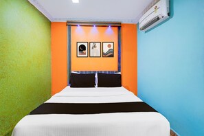 A hotel room with a bed, a wall-mounted air conditioner, and three framed artworks above the bed. - Classic Kvs Residency (Katpadi)