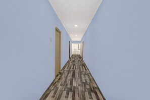 Un largo pasillo con piso estampado, paredes azul claro y una puerta a la izquierda.