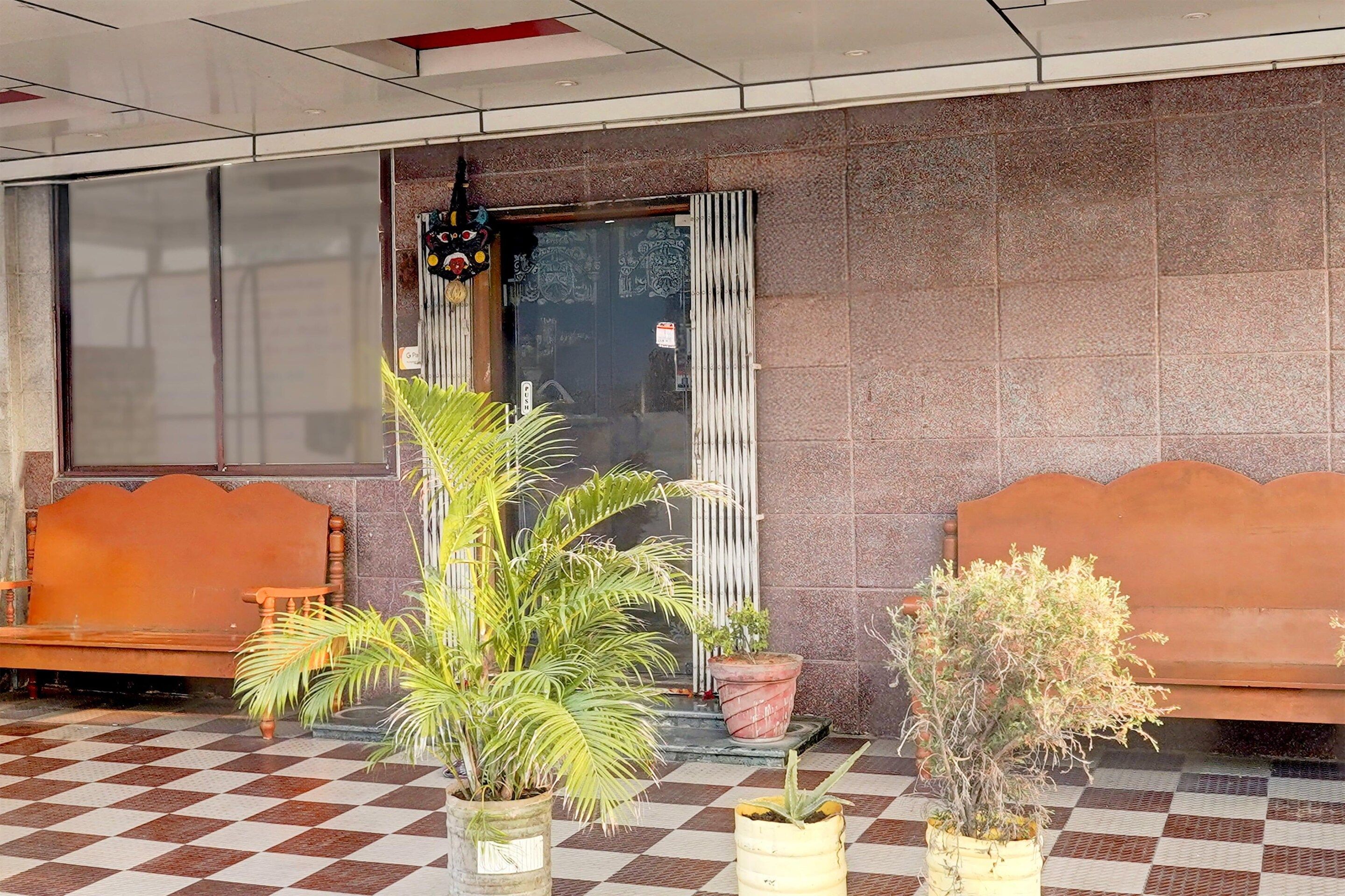 A reception area with a checkered floor, two wooden benches, and potted plants.