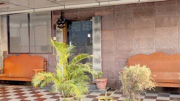 A reception area with a checkered floor, two wooden benches, and potted plants.