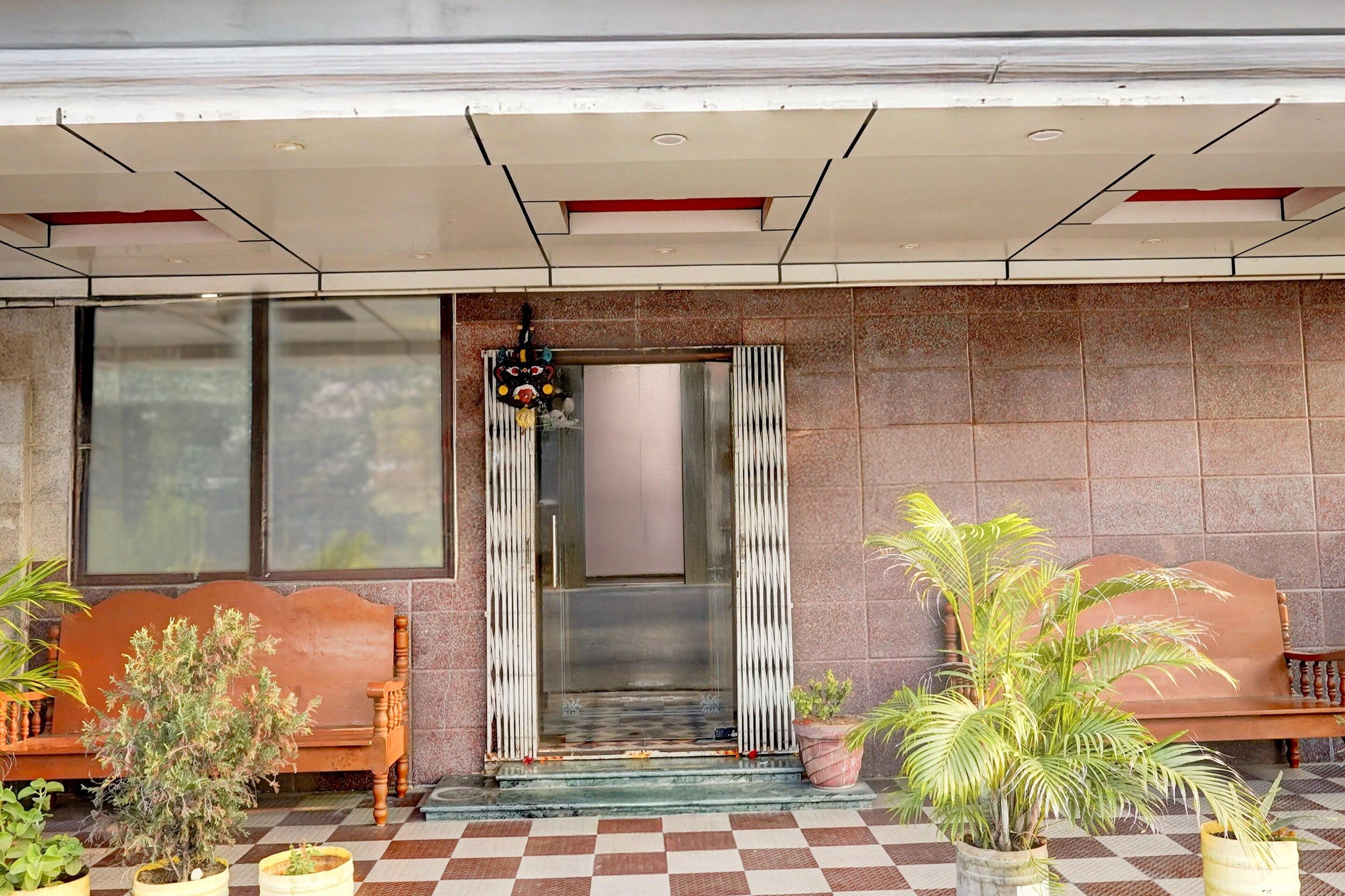 Entrada de hotel con piso de cuadros, un banco de madera y plantas en macetas.