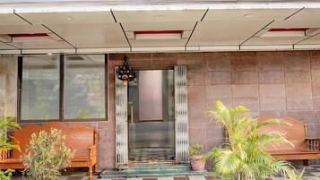 Entrada de hotel con piso de cuadros, un banco de madera y plantas en macetas.