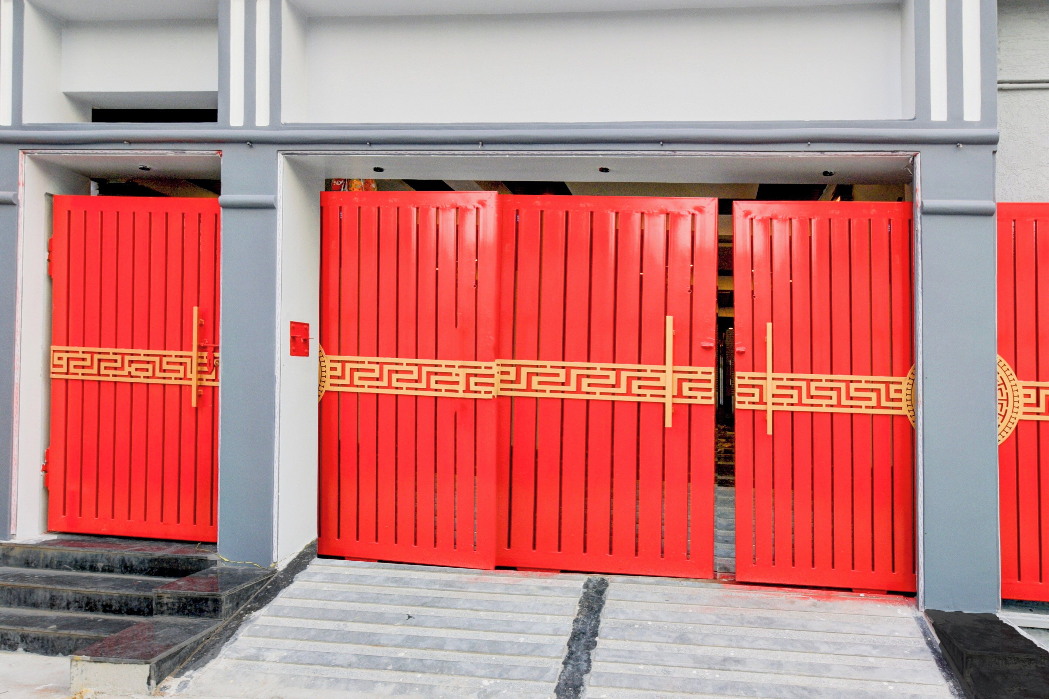 Un conjunto de puertas dobles rojas con un diseño decorativo, que dan acceso a la entrada de un edificio.