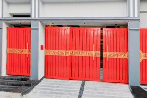 Un conjunto de puertas dobles rojas con un diseño decorativo, que dan acceso a la entrada de un edificio.
