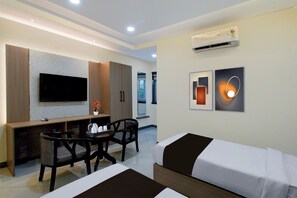 Una habitación de hotel moderna con cama, escritorio, silla, televisor y obras de arte en la pared.