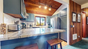 Eine moderne Küche mit Marmorarbeitsplatte, Holzboden und eingebauten Geräten.