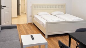 A room with a bed, a sofa, a small table with a remote control, and a chair. - The Vienna Nest 2BR near Westbahnhof (Vienna)