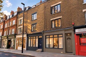 A row of brick buildings with ground-floor shops, including a restaurant and a specialist service provider. - Kings Cross 1-bed Apt, Sleeps 3 With Great Views (London)