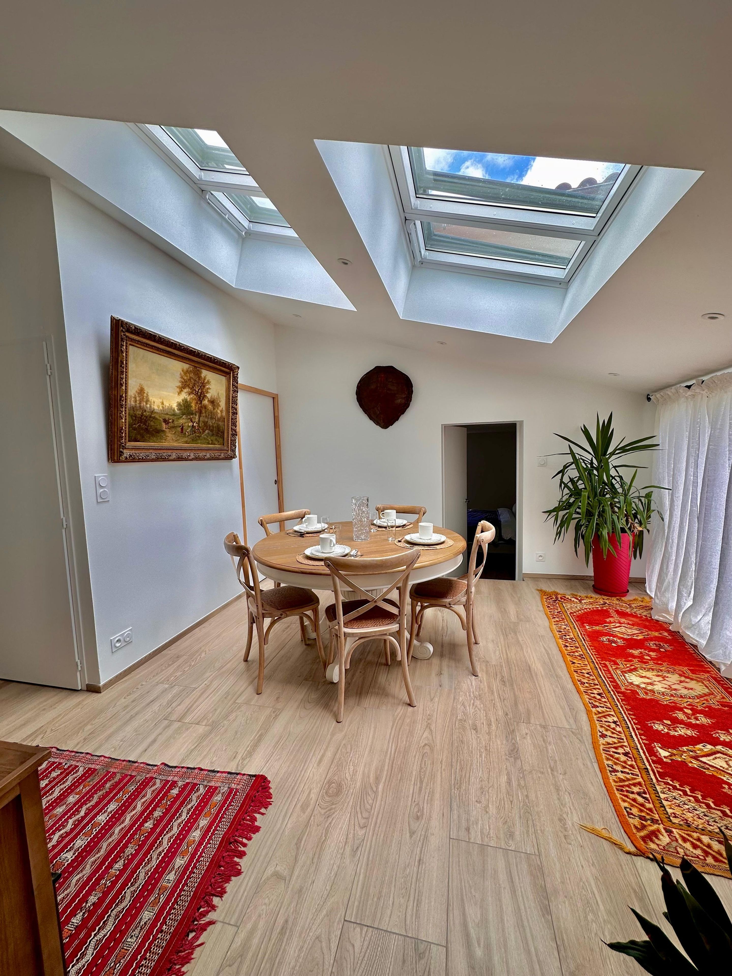 Un coin repas avec une table ronde, des chaises et un tableau accroché au mur.