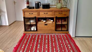 Une pièce avec un meuble en bois, un tapis rouge à motifs et une plante en pot.