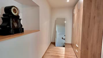 Ein Korridor mit Holzboden, einem Holzschrank und einem Regal mit einer Uhr.