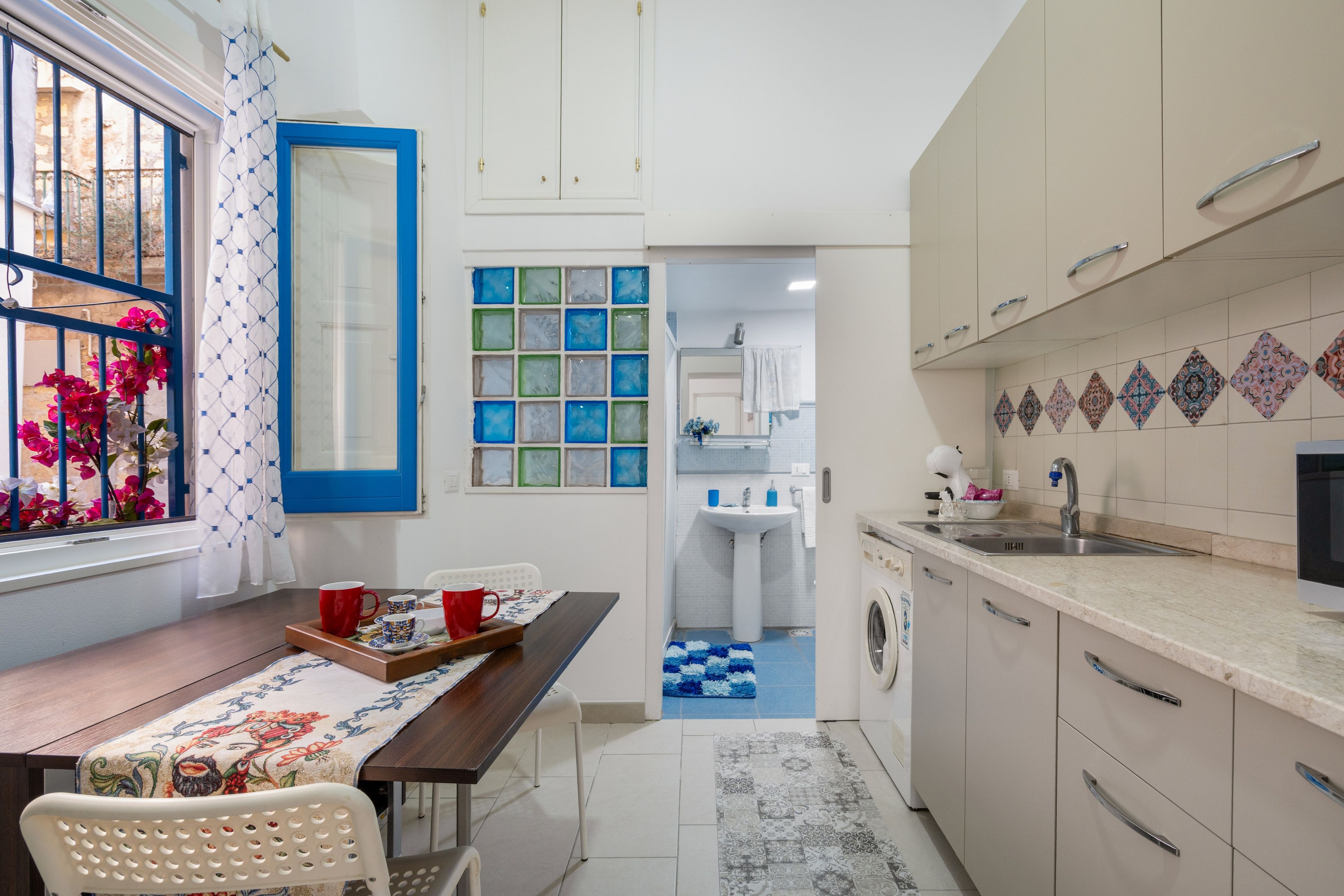 Una cucina compatta con zona pranzo, lavatrice e lavello.