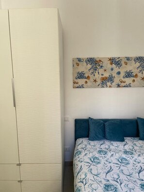 Una camera da letto con un letto, un armadio e un'opera d'arte appesa al muro.