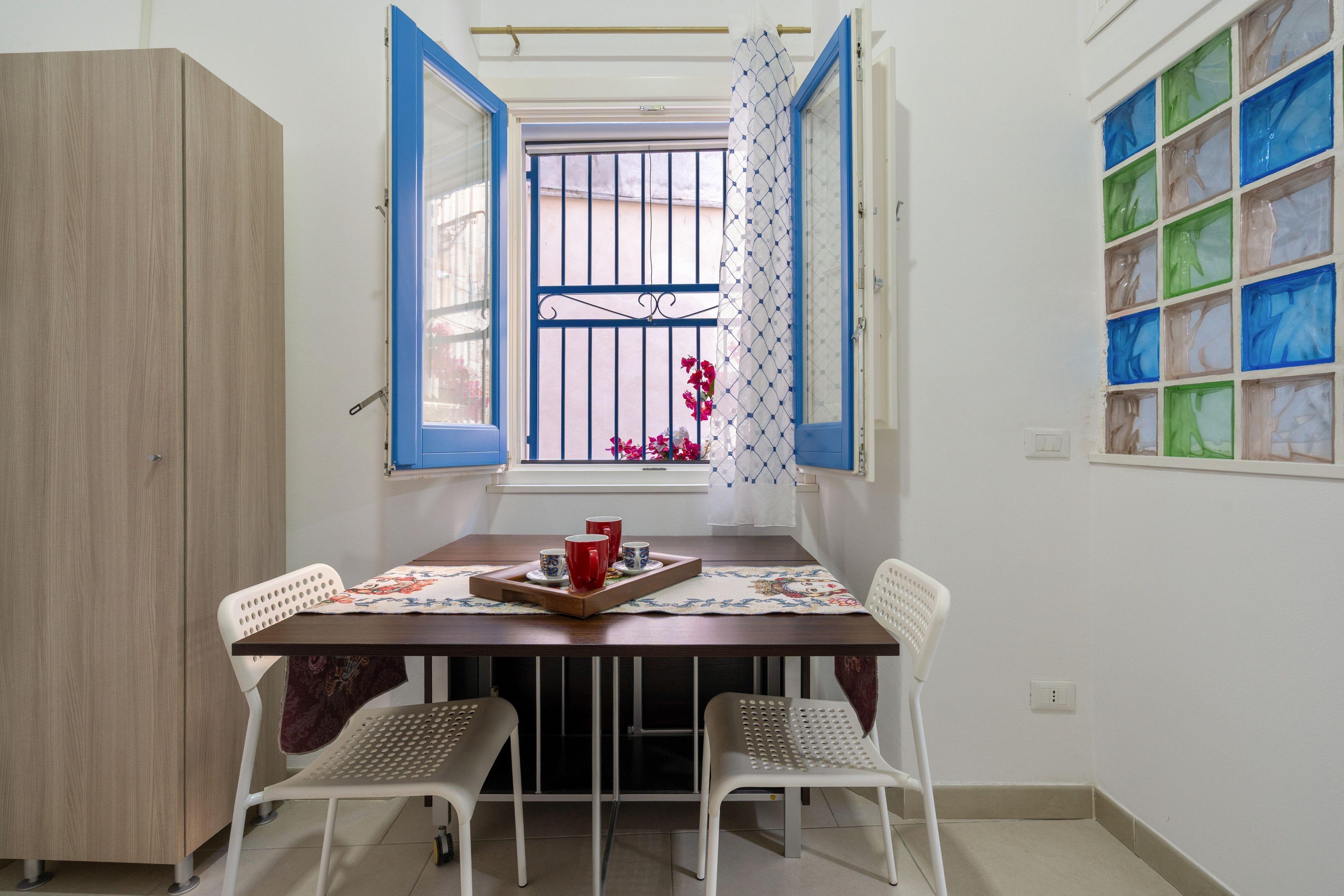 Zona pranzo con tavolo, sedie e una finestra con persiane blu.