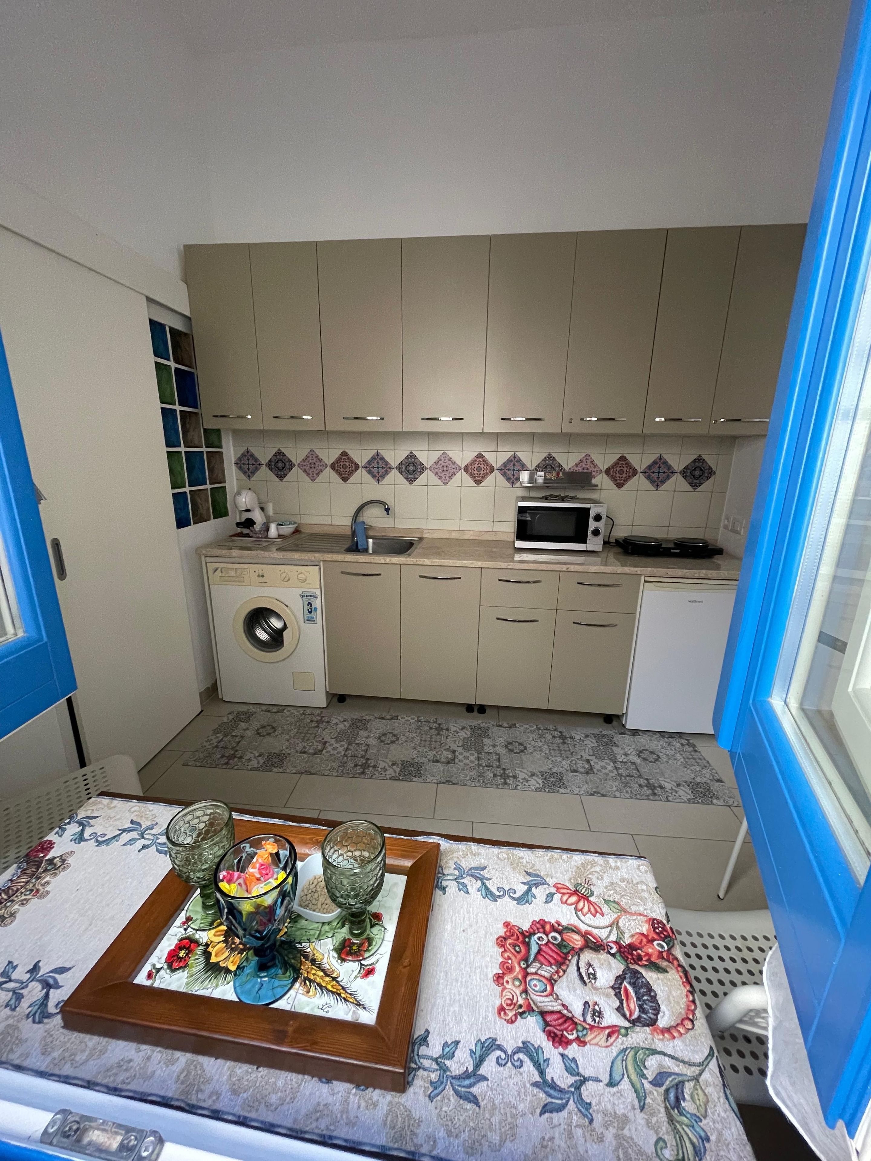 Una cucina funzionale con lavatrice, forno a microonde e lavello.