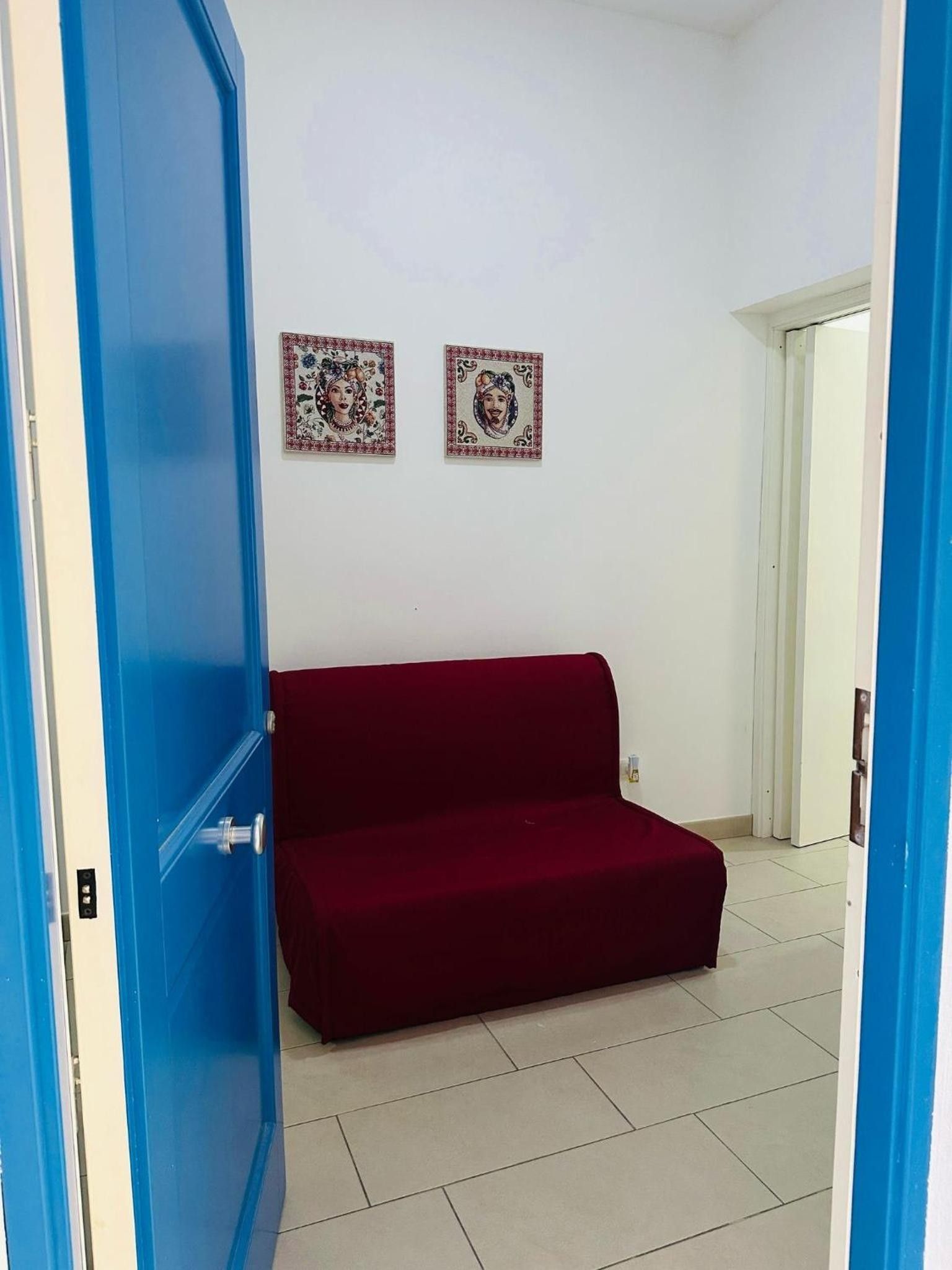 Una stanza con un divano rosso, una porta blu e due opere d'arte incorniciate al muro.