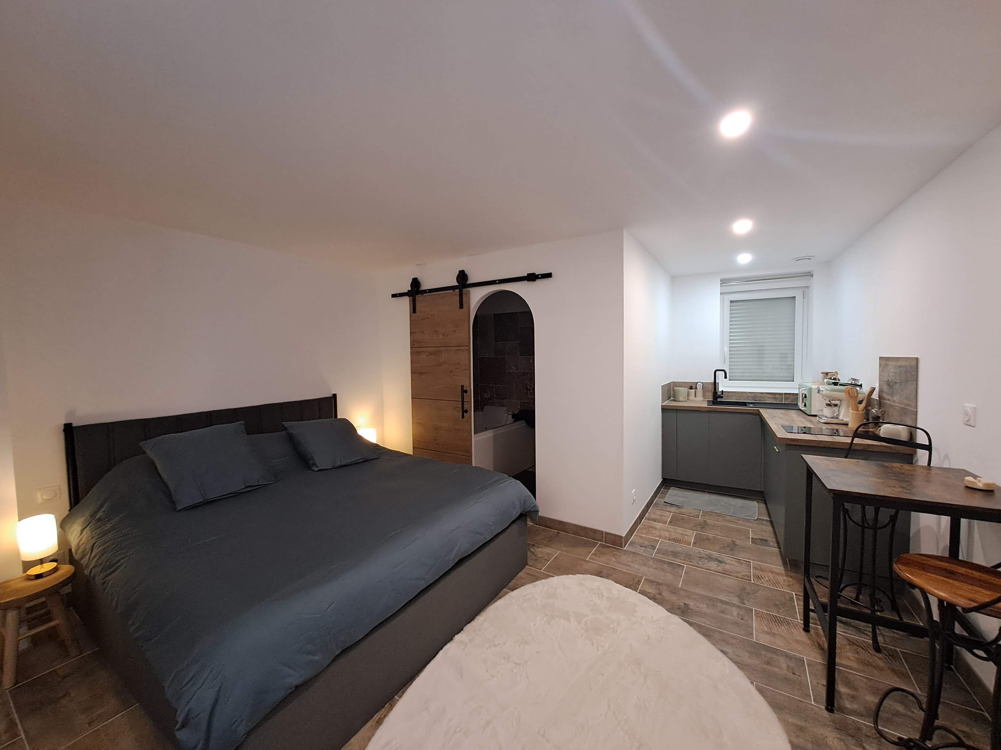 Una camera compatta con un letto, un comodino e un angolo cottura piccolo.