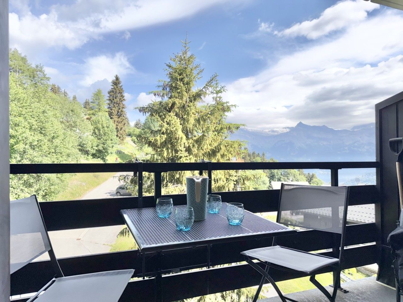 Un balcon avec une table, des chaises et un ordinateur portable.