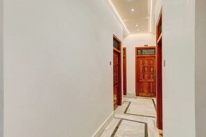 A hallway with wooden doors and a marble floor. - Townhouse Vishwanath Temple Varanasi (Varanasi)
