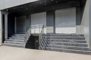 A set of marble stairs leading to a building entrance with closed shutters and a security camera. - Townhouse Vishwanath Temple Varanasi (Varanasi)