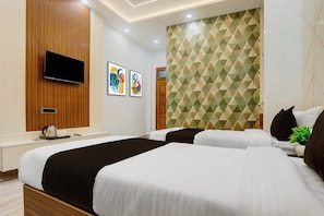 A hotel room with a large bed, a flat-screen TV mounted on a wooden panel, and two framed artworks on the wall. - Townhouse Vishwanath Temple Varanasi (Varanasi)
