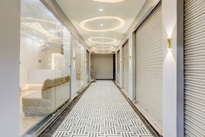 A hallway with patterned flooring, recessed ceiling lighting, and closed shutters on the right. - Townhouse Vishwanath Temple Varanasi (Varanasi)