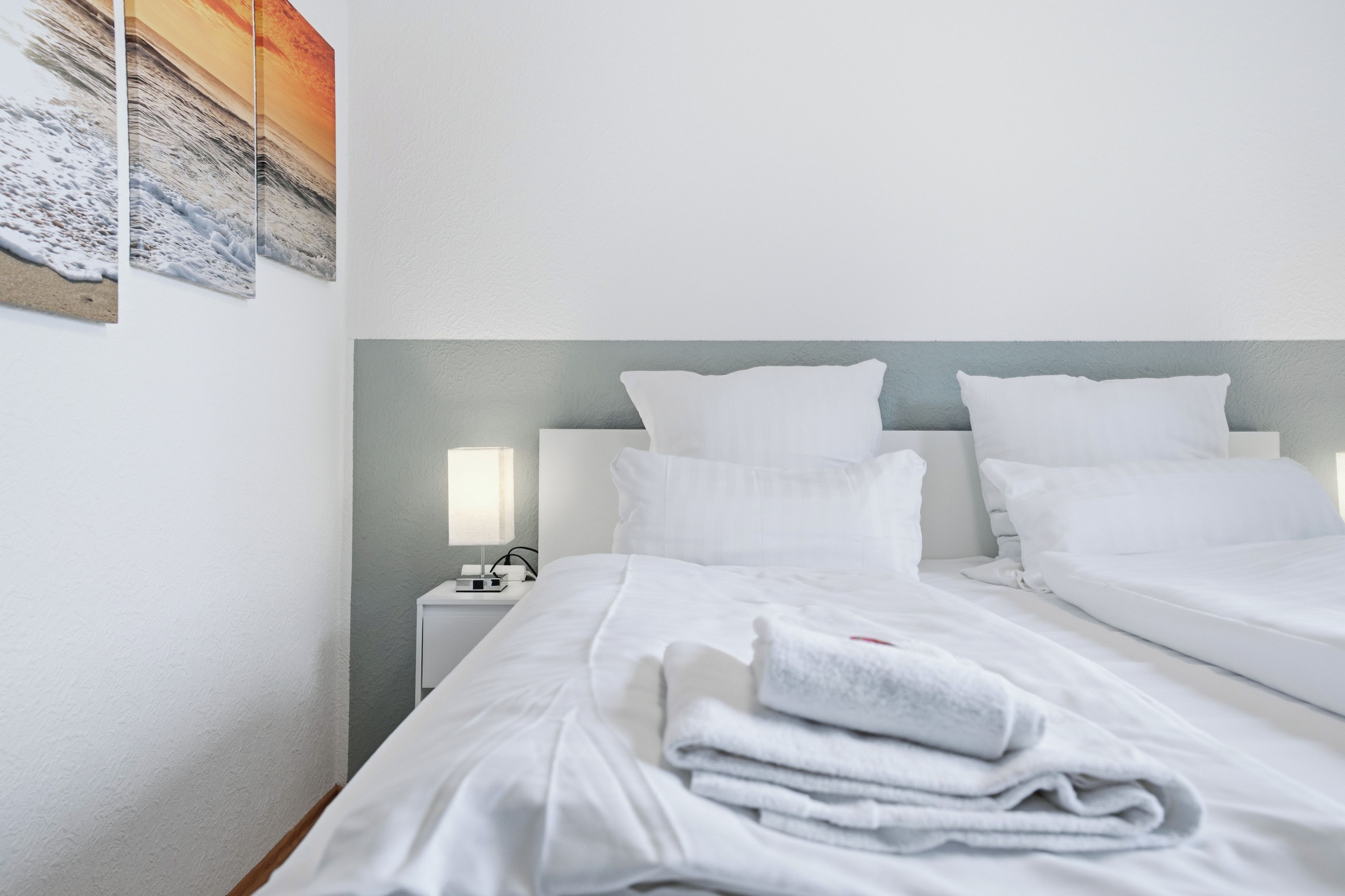 Ein Hotelzimmer mit zwei Betten, einem Nachttisch mit Lampe und einem Bild an der Wand.