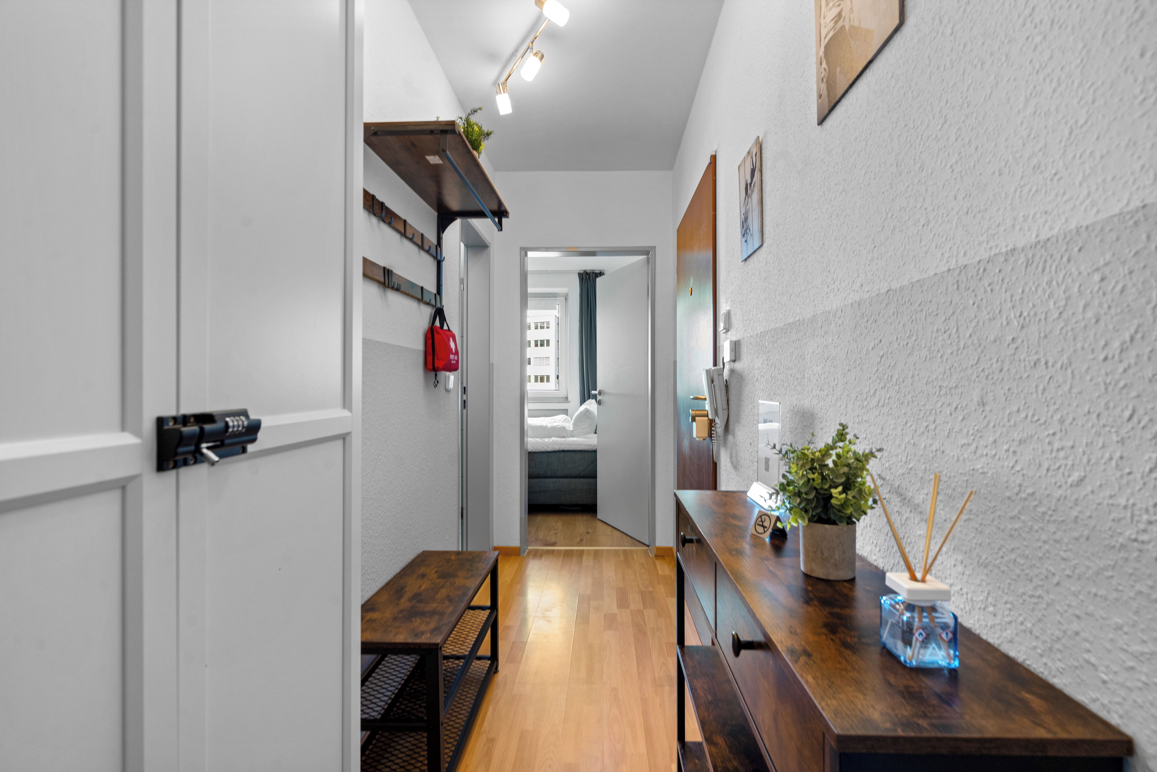 A narrow hallway with a wooden bench, a small table, and a potted plant.