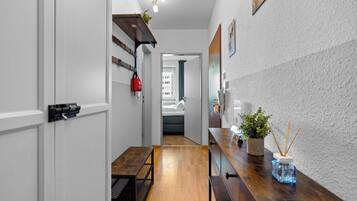 A narrow hallway with a wooden bench, a small table, and a potted plant.