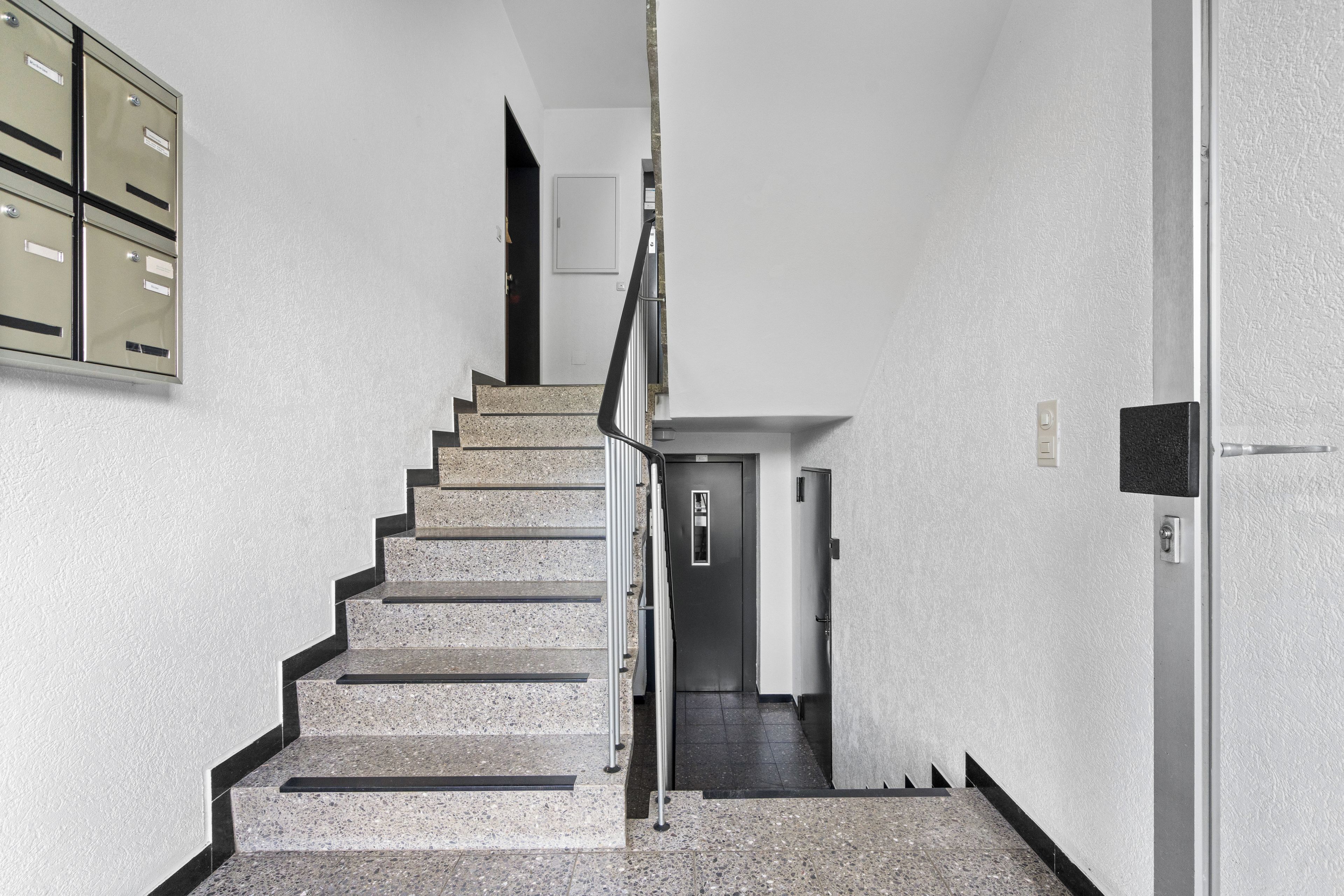 Eine Treppe mit Metallgeländer, die zu einer Tür oben führt.
