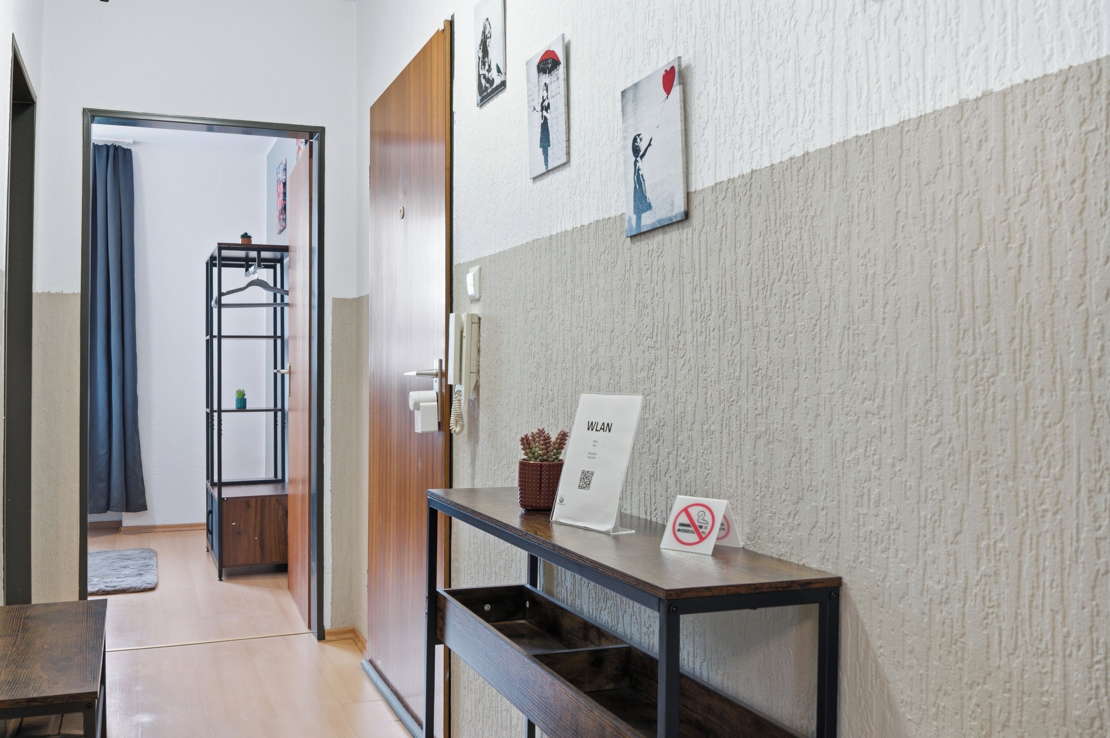 A hallway with a wooden door, a coat rack, and a sign with 'WLAN' on it.