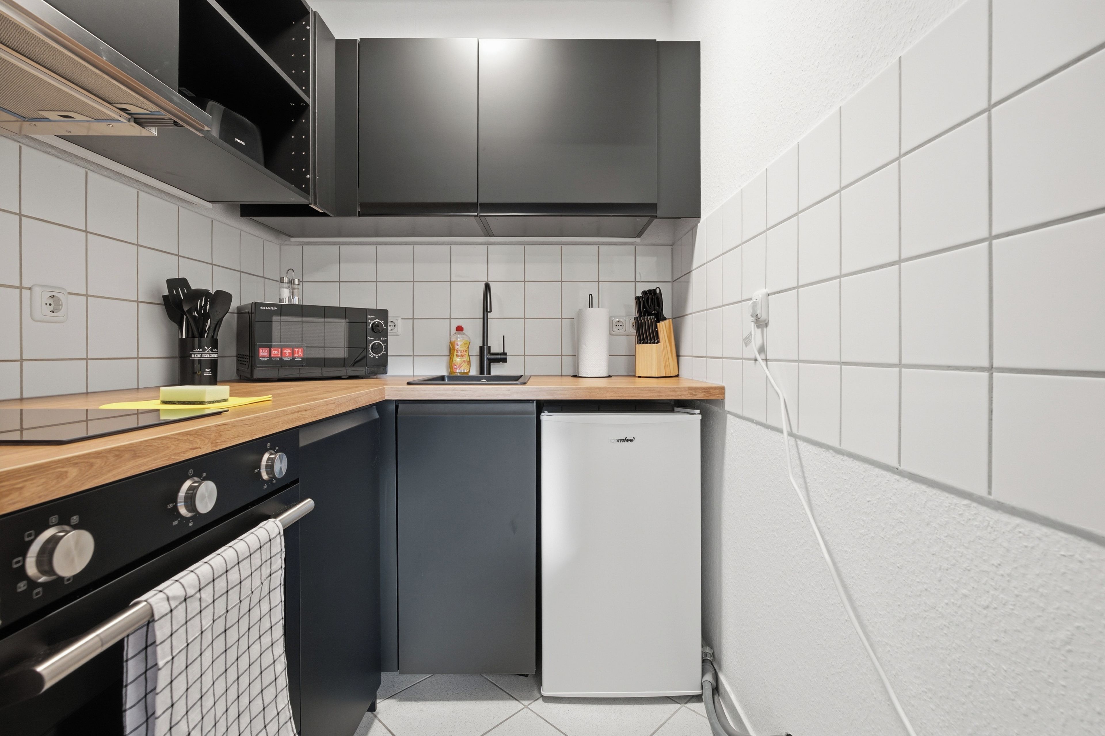 Eine kompakte Küche mit Mikrowelle, Herd und Kühlschrank.