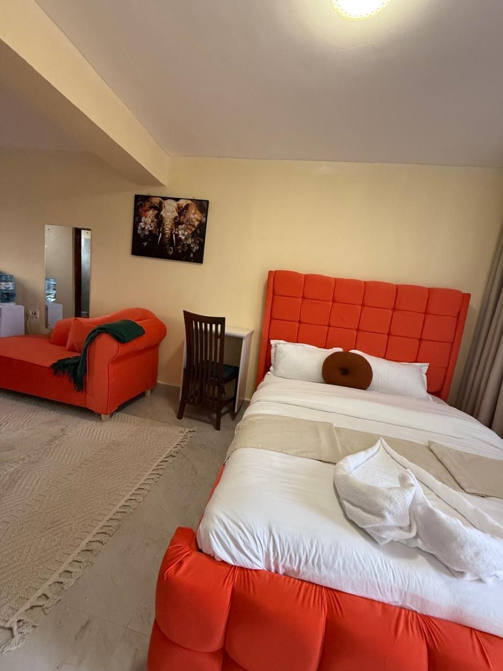 A hotel room with a bed, a chair, a small table, a sofa, and a painting on the wall.