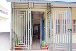 Una entrada tancada amb un paviment de rajoles, una porta blava i plantes en testos.